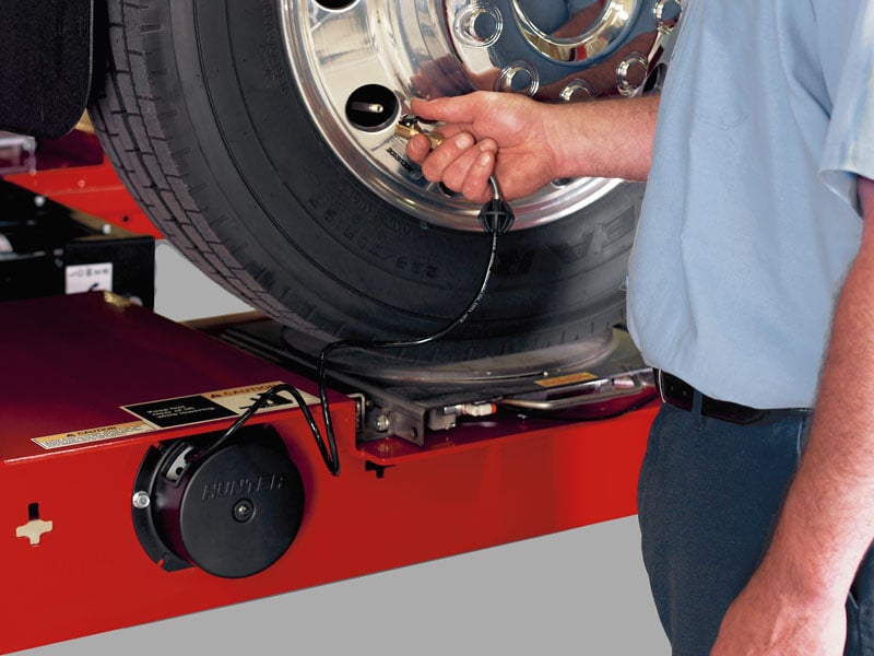 technician using inflation station on four post lift