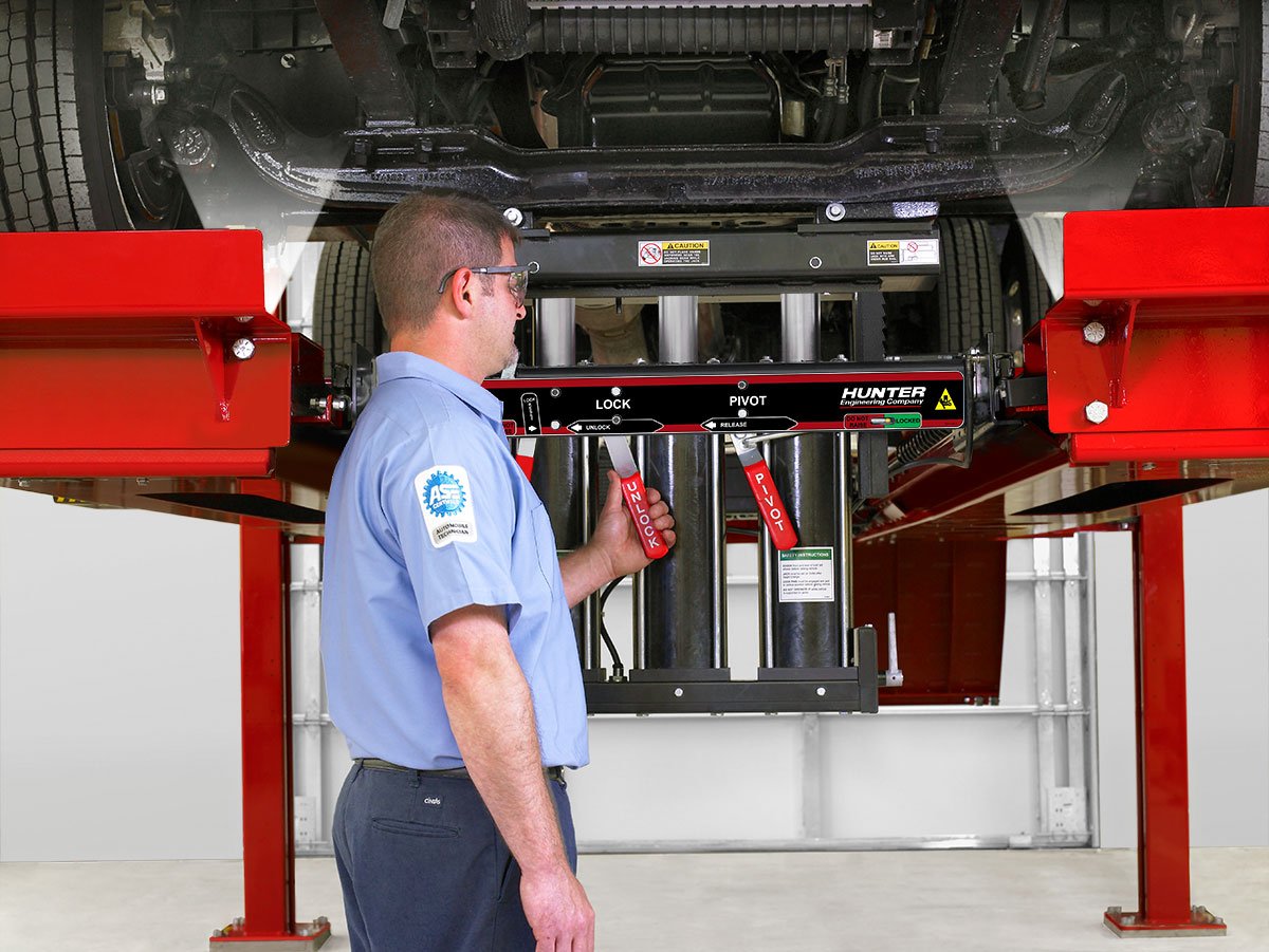 technician unlocking swing air jacks on four post lift