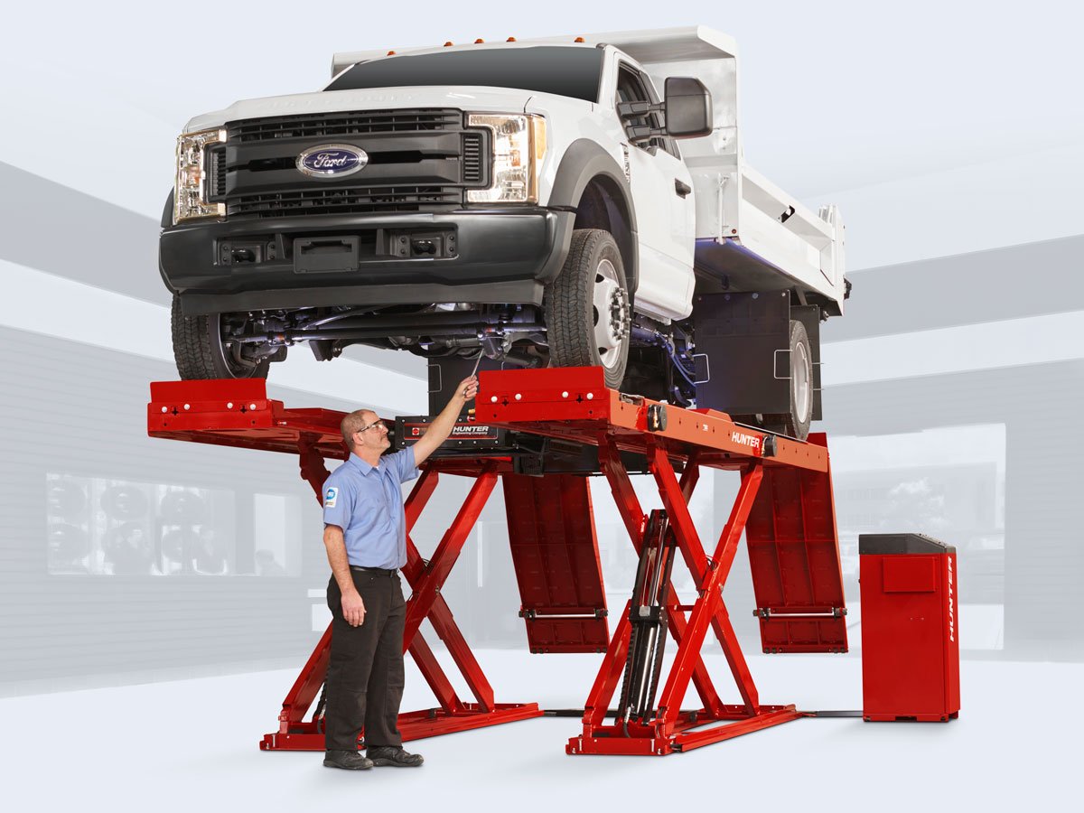 technician servicing white truck under alignment lift rack