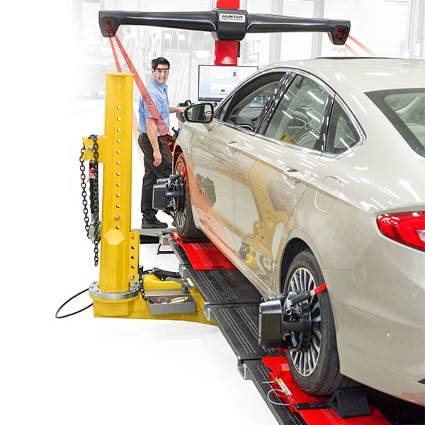 technician performing collision alignment with hunter aligner on frame rack