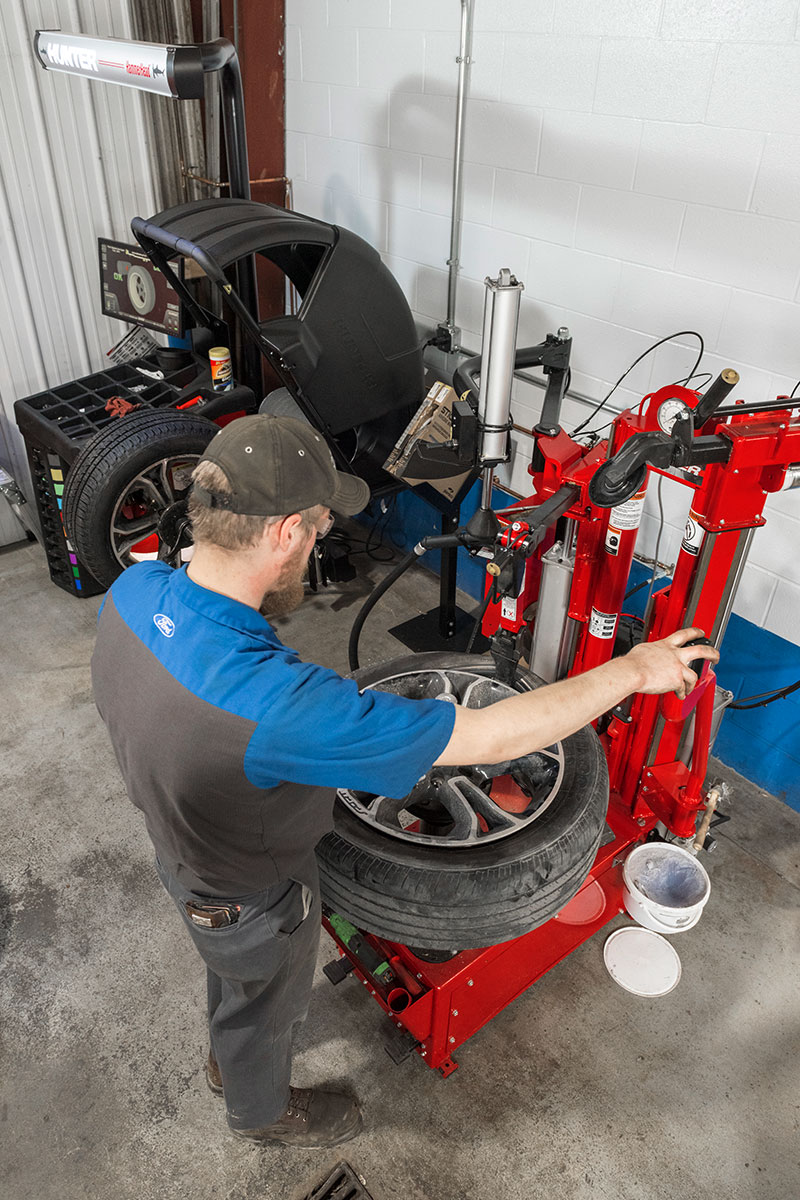 tc-tc39-realshop-auffenbergford5.jpg tech using polymer tool head on hunter tire changer