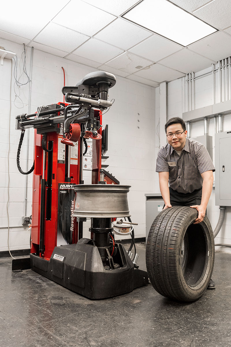 tc-tcr-realshop-martycancilla3.jpg operator smiling at camera while rolling tire next to revolution tire changer
